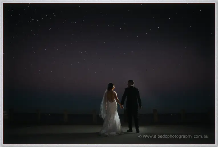 Domenica and Adrian walk hand in hand beneath a vast starry sky on the Acqua Viva waterfront