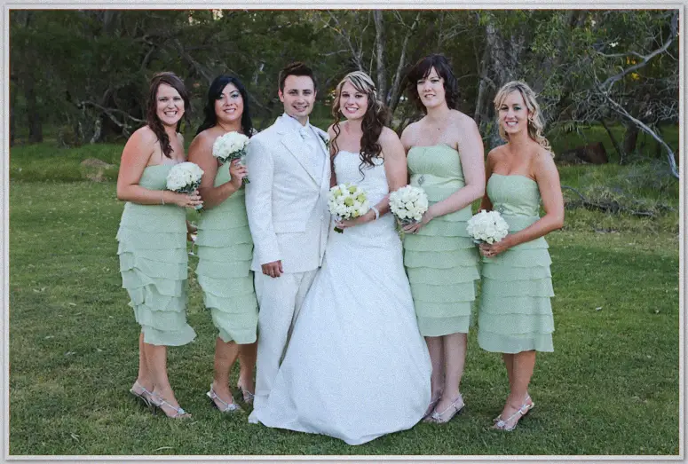 Bridal party on the grass, Simon in white beside Lauren and four bridesmaids in sage with bouquets