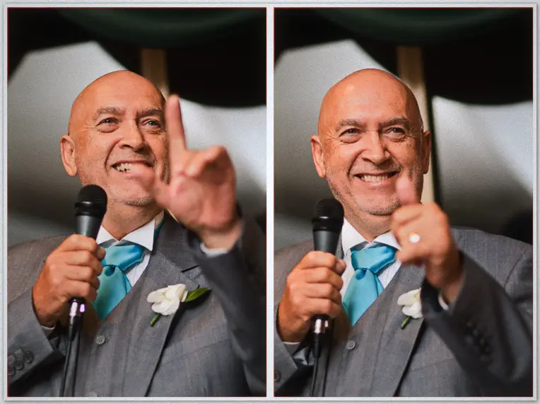 A bald groomsman in a grey suit and turquoise tie grins and points mid-speech at the reception