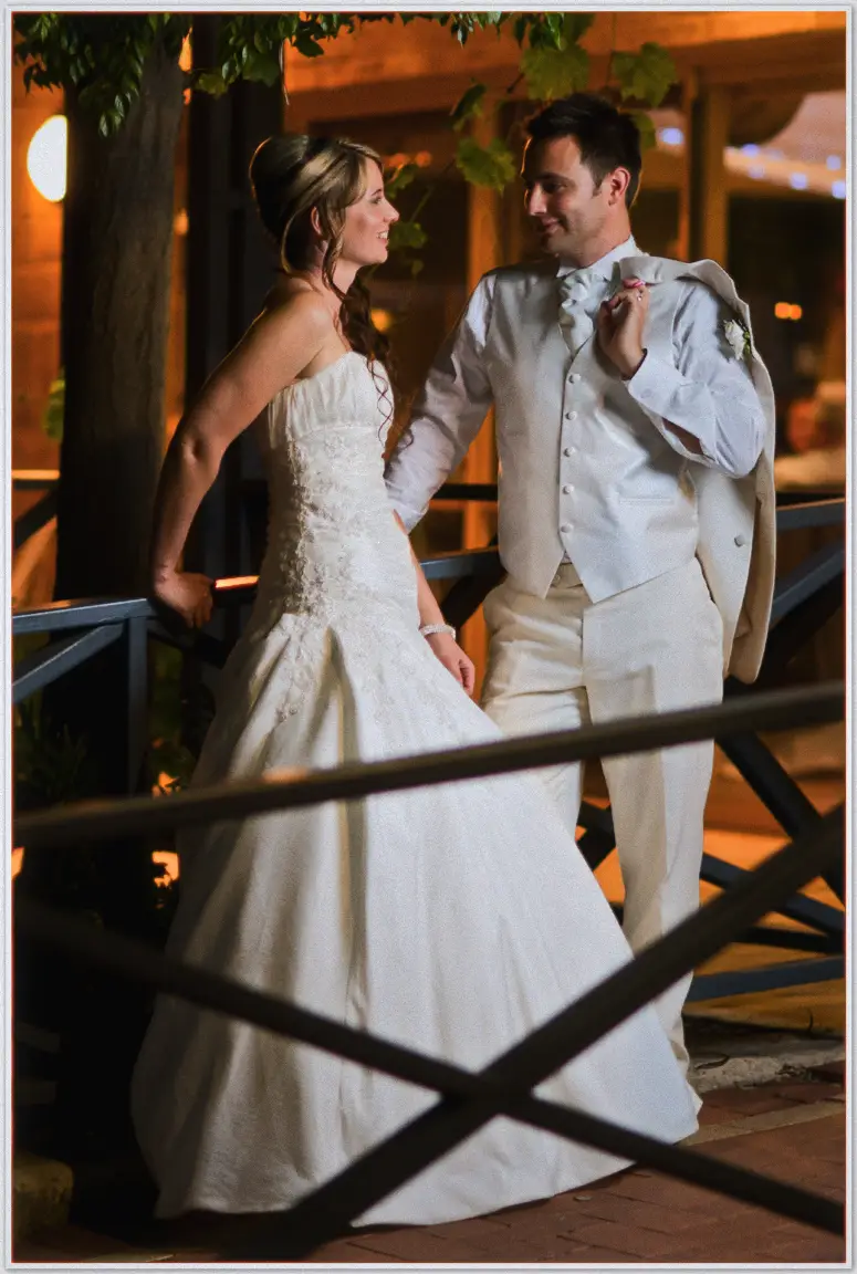 Lauren and Simon laugh together on a lamp-lit walkway, his jacket over his shoulder at night