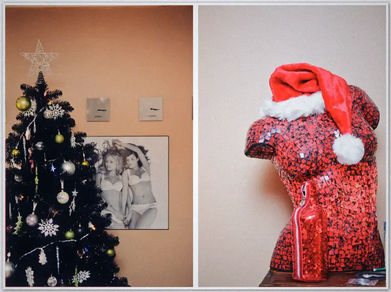 Black Christmas tree with gold baubles beside red mosaic torso mannequin wearing Santa hat, quirky interior