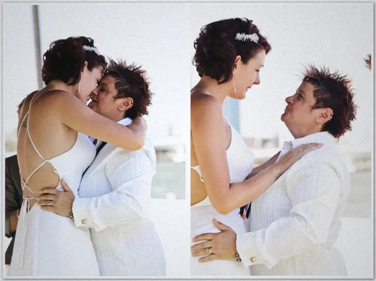 Brides embrace and gaze at each other after their ceremony, sparkling white waterfront light