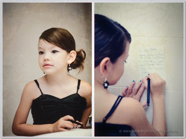 Fremantle Wedding | Charlene and Phil A young flower girl in black inspects her earrings before scribbling a note to Charlene and Phil