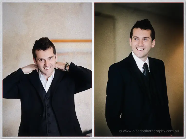 Fremantle Wedding | Charlene and Phil A groomsman grins as he settles his black suit jacket beside a warmly lit hallway portrait