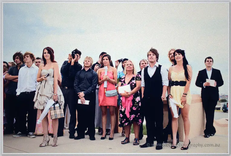 Fremantle Wedding | Charlene and Phil Wedding guests in summer dresses and dark shirts gather along a terrace beneath an overcast sky