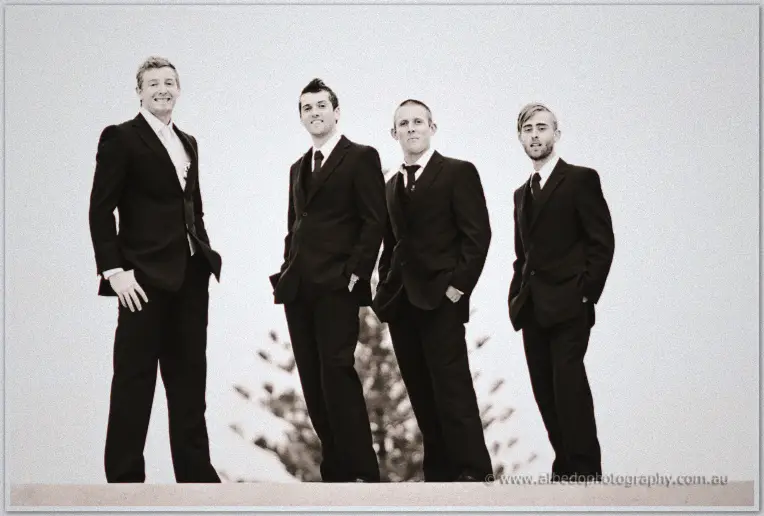 Fremantle Wedding | Charlene and Phil Phil and his groomsmen loom cheerfully in black suits over a pale overcast sky