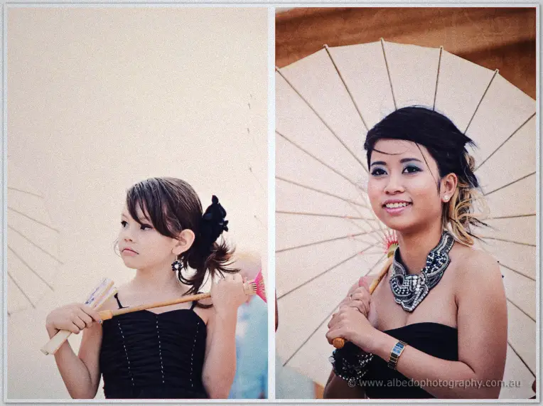 Fremantle Wedding | Charlene and Phil A flower girl and a bridesmaid pose with paper parasols against the pale sky after the ceremony