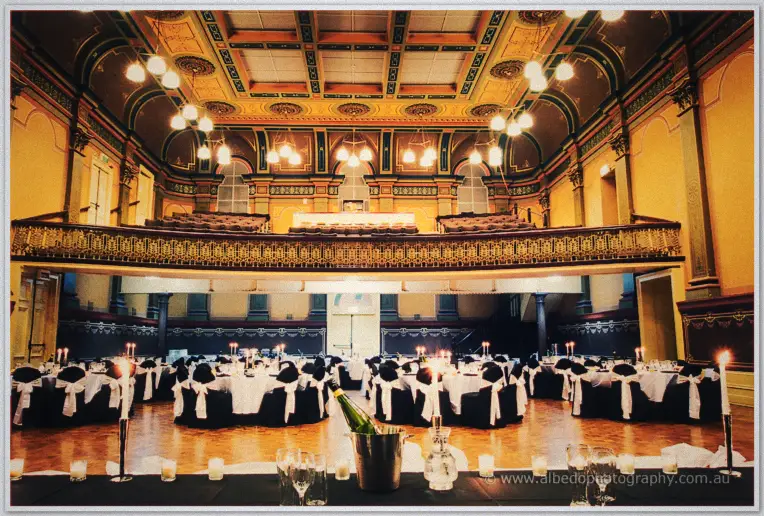 Fremantle Wedding | Charlene and Phil Candlelit round tables await guests beneath the ornate ceiling and balcony of a heritage hall in Fremantle