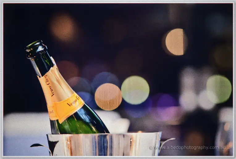 A champagne bottle chills in a silver ice bucket against warm evening bokeh