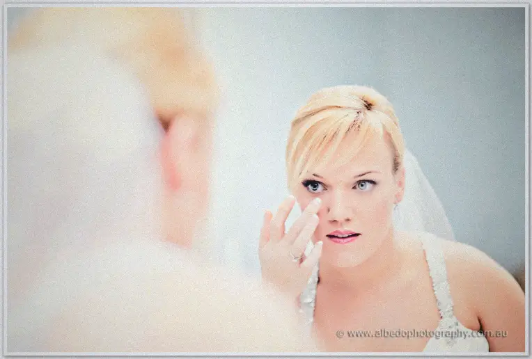 Emily checks her reflection in the mirror, veil pinned and ring on show