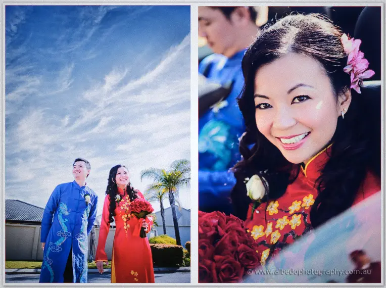 Michelle and Khoa in red and blue ao dai stand beneath wispy clouds in a sunlit outdoor portrait.