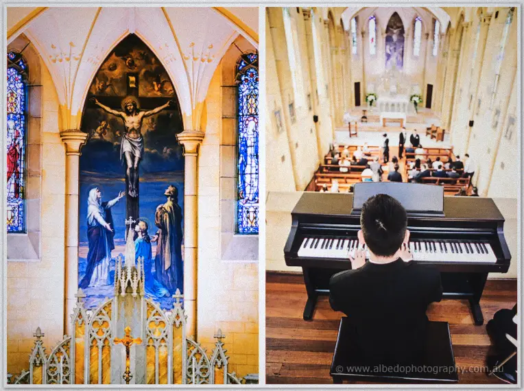 Ornate crucifix mural and stained glass inside the gothic church while a pianist plays before seated guests.
