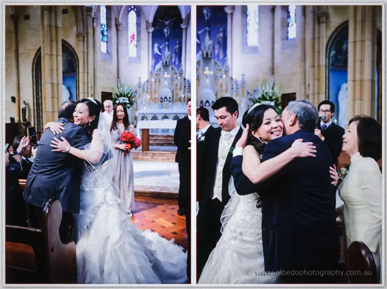 Michelle embraces her father and mother at the church front, joy on every face, her bouquet resting nearby.
