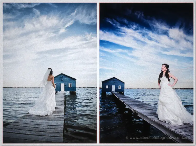 Michelle and Khoa stand arm in arm on the jetty, the blue boatshed beyond them at dusk.