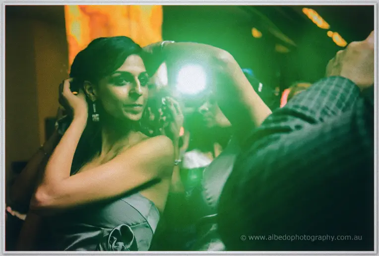 Lydia sweeps her hair back under a flare of green light, lost in the music