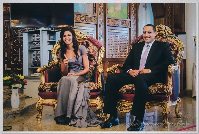 Lydia and Mina laugh from gilded throne chairs against the carved screens of the church