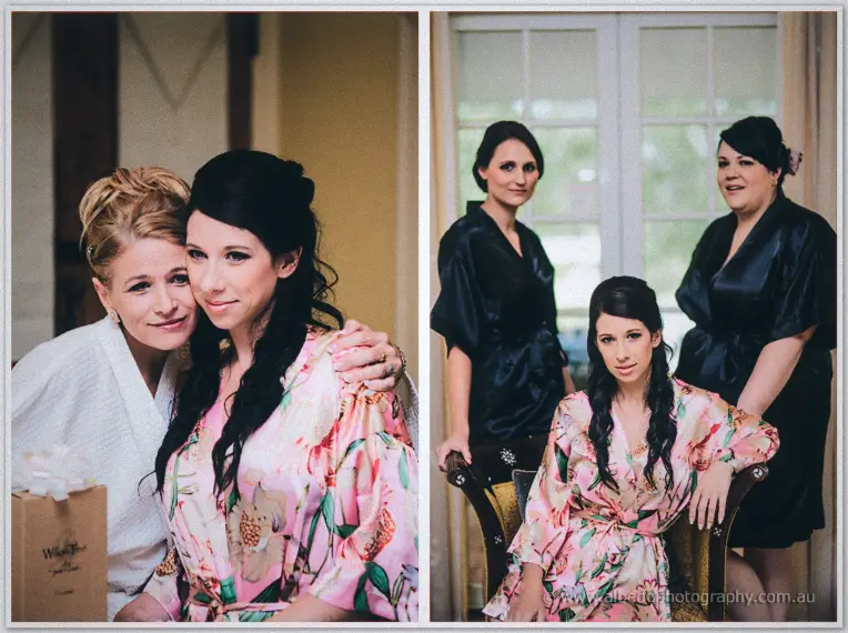 Sarah hugs a smiling friend in white while her bridesmaids flank her chair in matching black robes.
