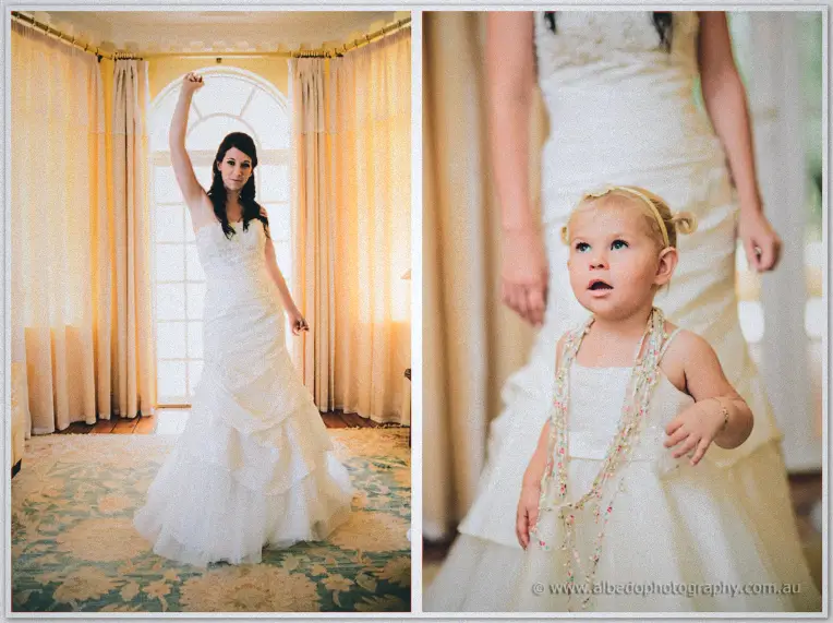 Sarah stretches an arm skyward in her gown as a little flower girl peeks up at her.