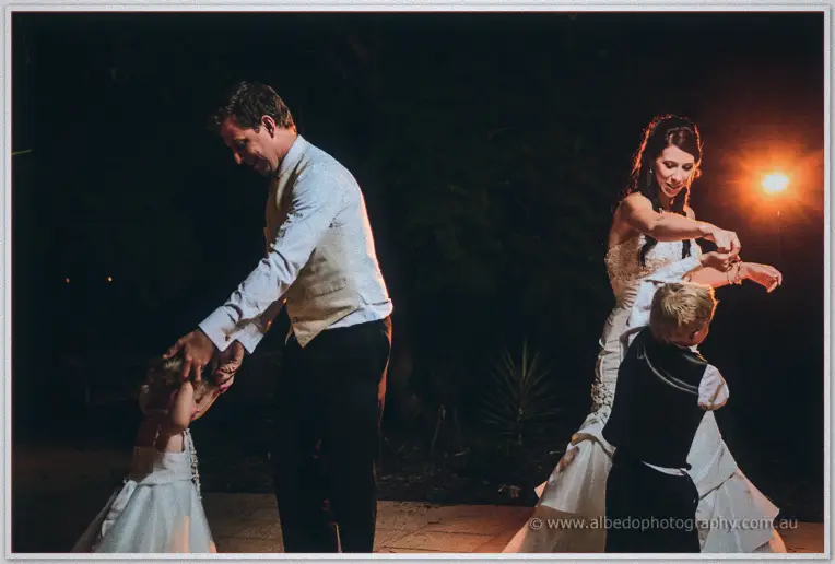 Daniel twirls the flower girl while Sarah dances with the page boy under the night lights.