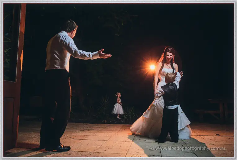 On the floodlit terrace Daniel reaches out as the page boy dances with laughing Sarah.