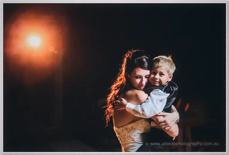 Sarah cradles the sleepy page boy in her arms as warm light flares through the night.