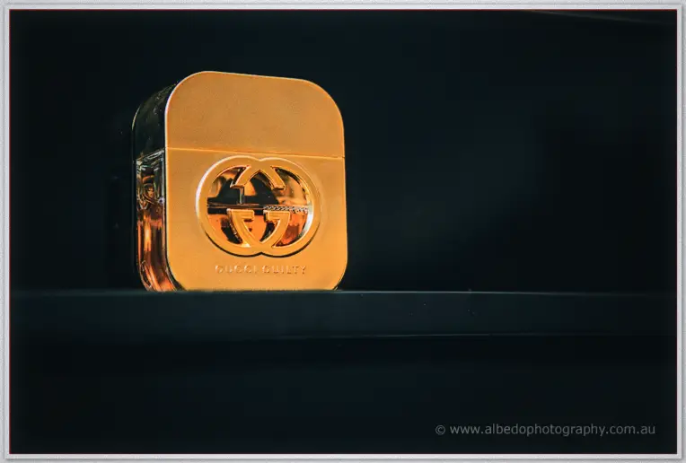 Golden perfume bottle glowing against a dark background on the dressing table