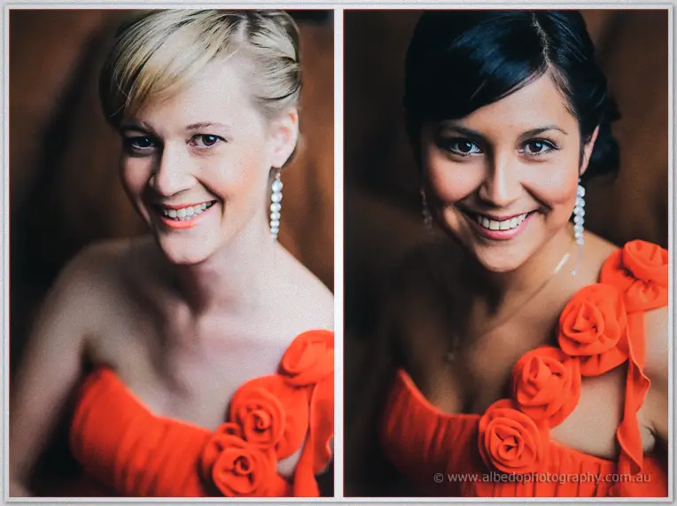 Two bridesmaids in tangerine rose-shoulder dresses beaming at the camera with pearl earrings