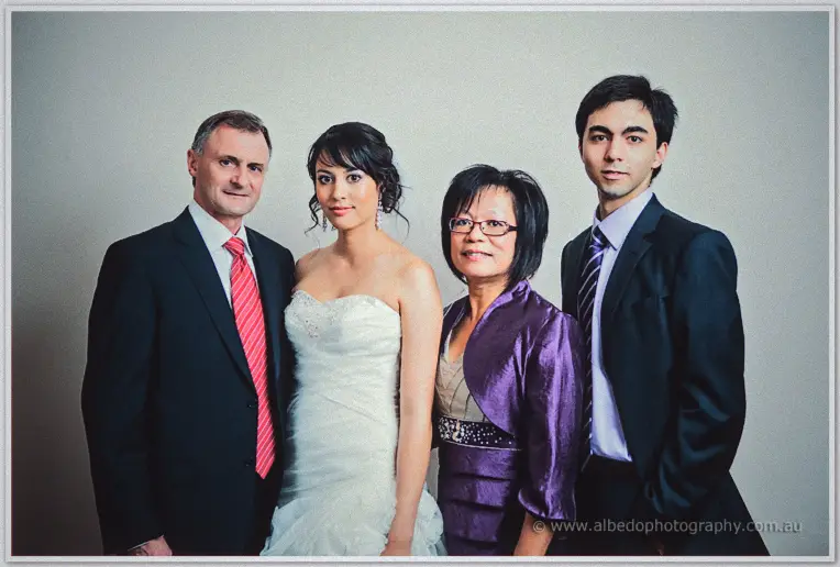 Sarah in her strapless gown posing with her parents and brother in soft indoor light