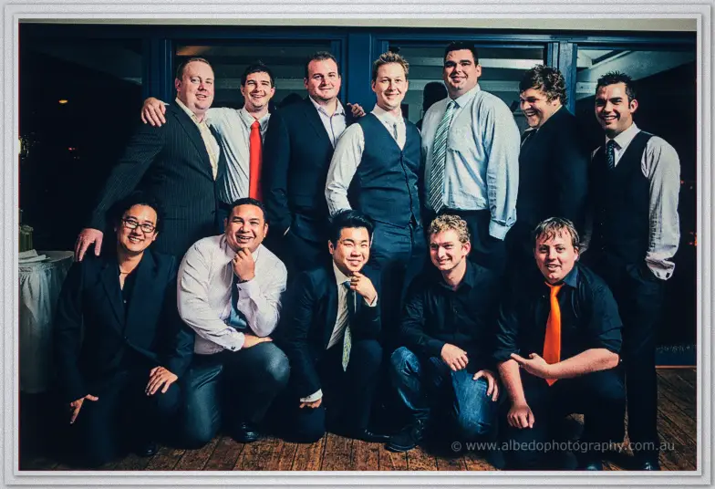 Shannon and a dozen friends cram into a two-row group shot, arms over shoulders in navy and grey