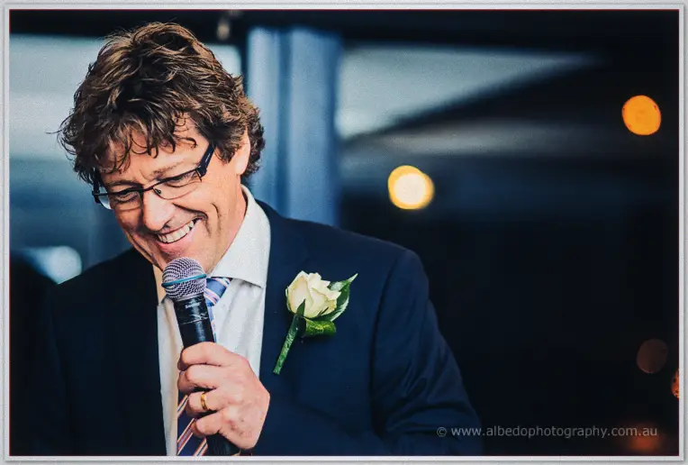 Shannon hides his face laughing while Sarah grins beside champagne flutes and gold double-happiness decor