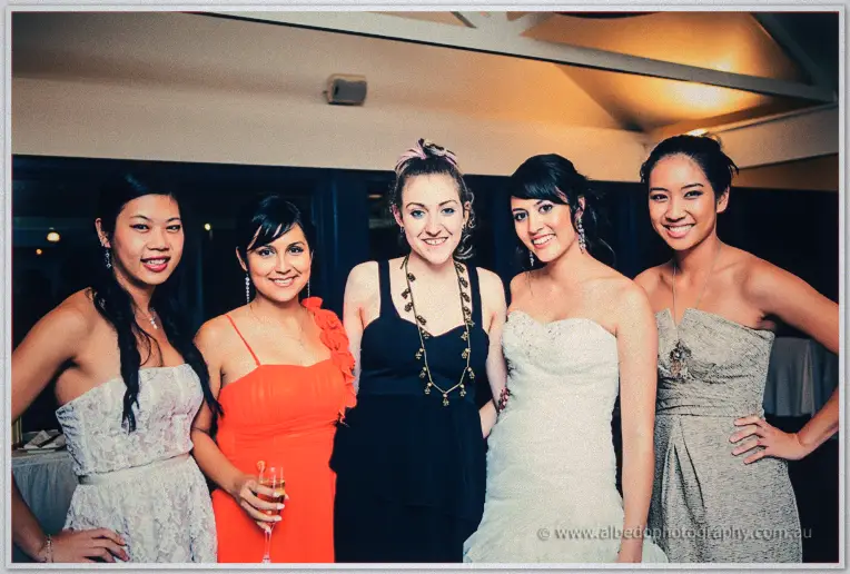 Sarah and four friends line up laughing, red and silver dresses around her strapless gown