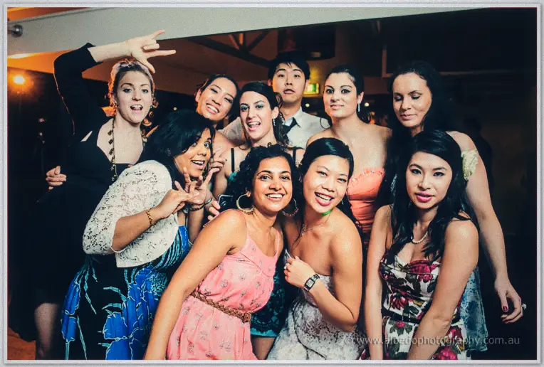 A big crowd of friends piles in for a group shot, flashing peace signs and rocking out