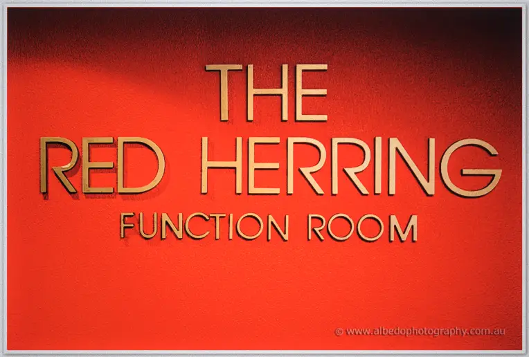 Gilt letters spelling The Red Herring Function Room across a red textured wall
