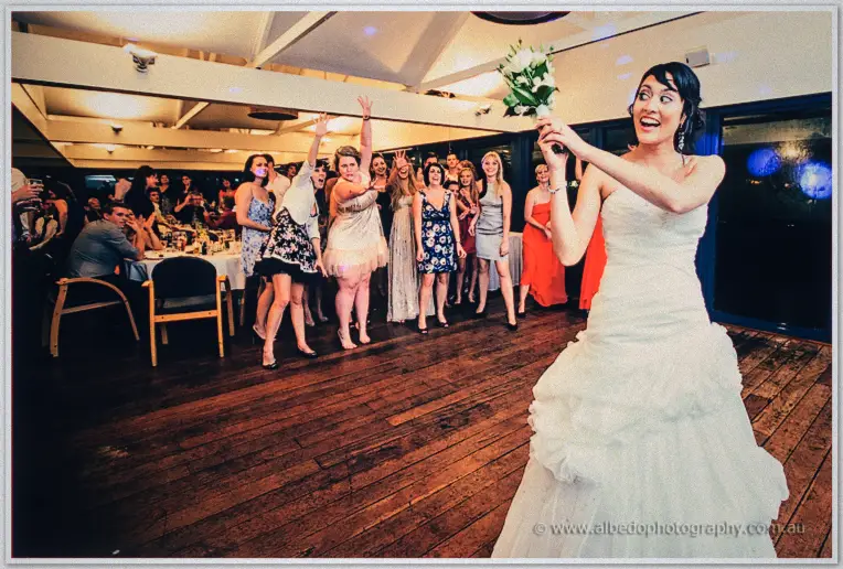 Sarah playfully aims her bouquet over her shoulder at the waiting line of guests
