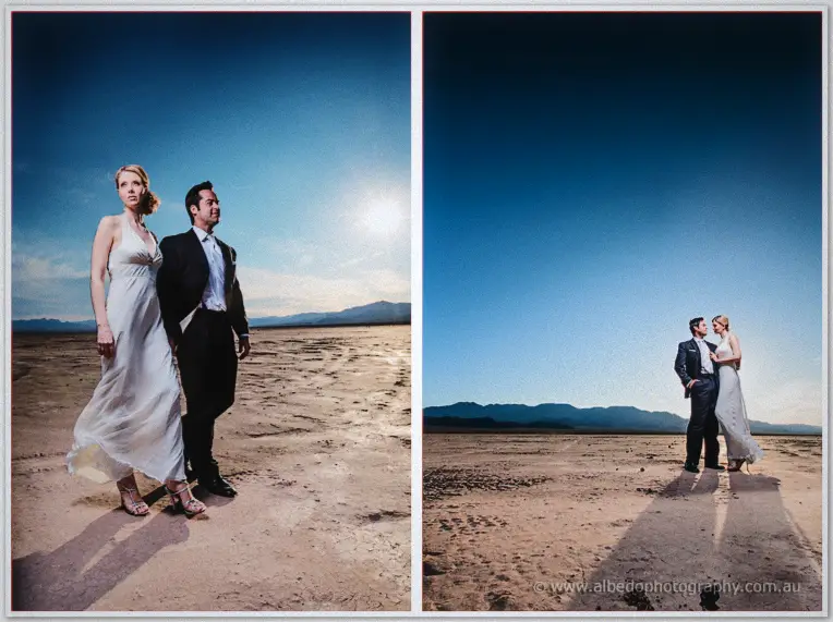 Couple walks the cracked lake bed hand in hand under a huge sunburst desert sky