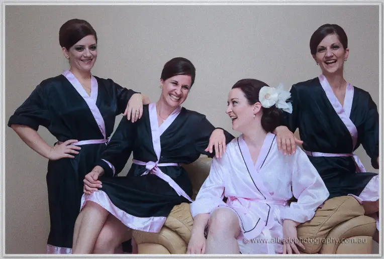 Felicity laughing with her bridesmaids in matching black and pink robes