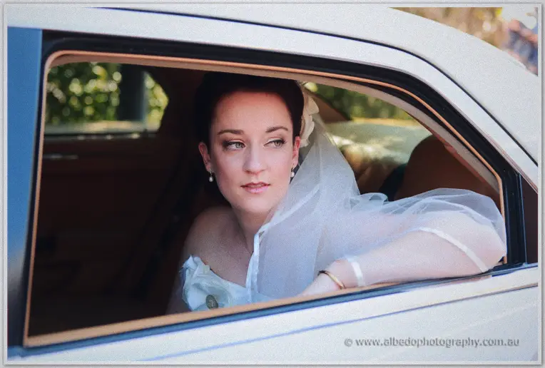 Felicity gazing thoughtfully from the limousine window, veil pooling at her arm