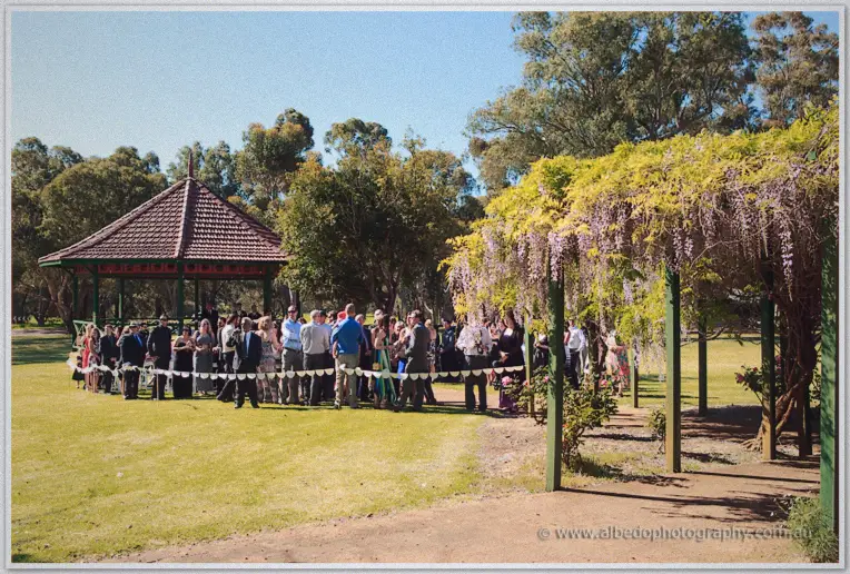 Guests mingling around the rotunda lawn beneath cascading wisteria