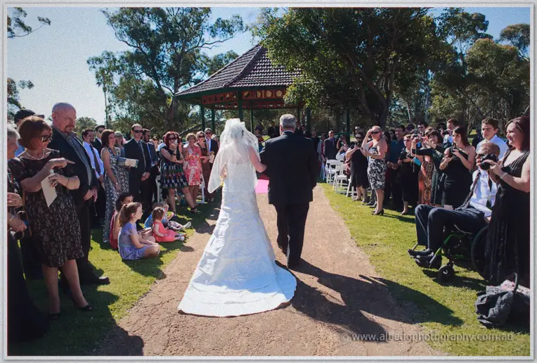 Felicity and her father walking the sandy aisle between rows of smiling guests