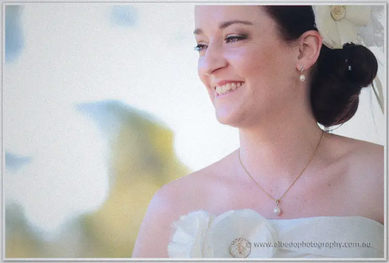Beaming Felicity in profile wearing pearl drops and a feathered hair flower