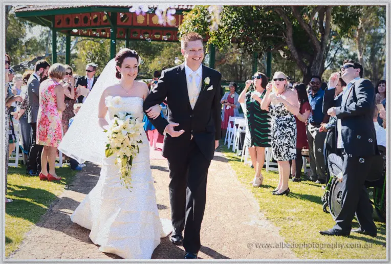 Felicity and Phil walking back down the aisle arm in arm through bubbles