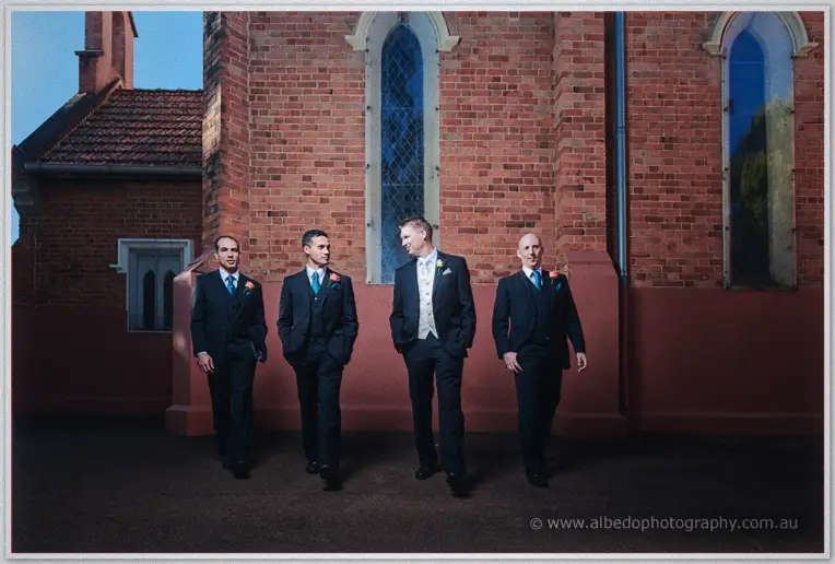 Phil strolling with his groomsmen past the church's stained-glass windows
