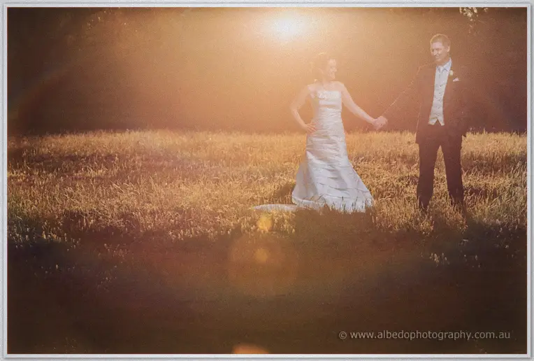 Hazy sunset silhouette of the couple hand in hand in the tall grass