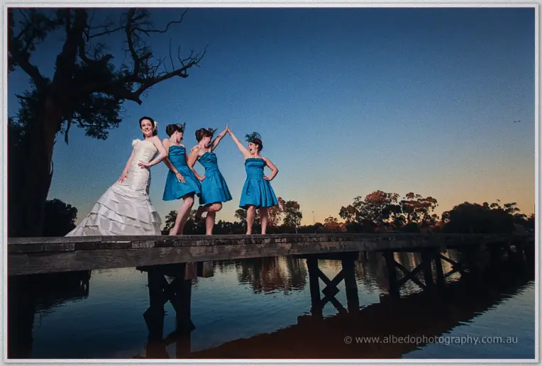 Felicity and her bridesmaids in teal gowns strike playful poses on the Guildford Landing jetty