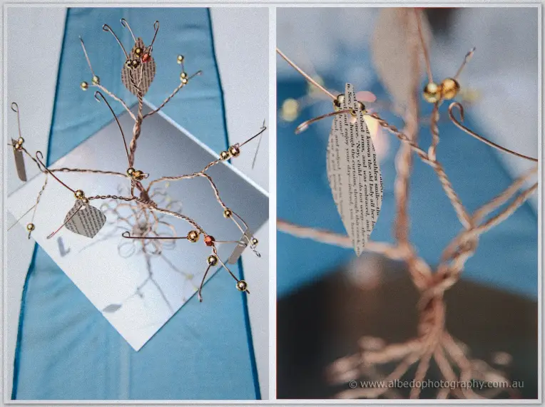 A handcrafted copper wire wish tree with paper leaves and gold beads waits for guest messages