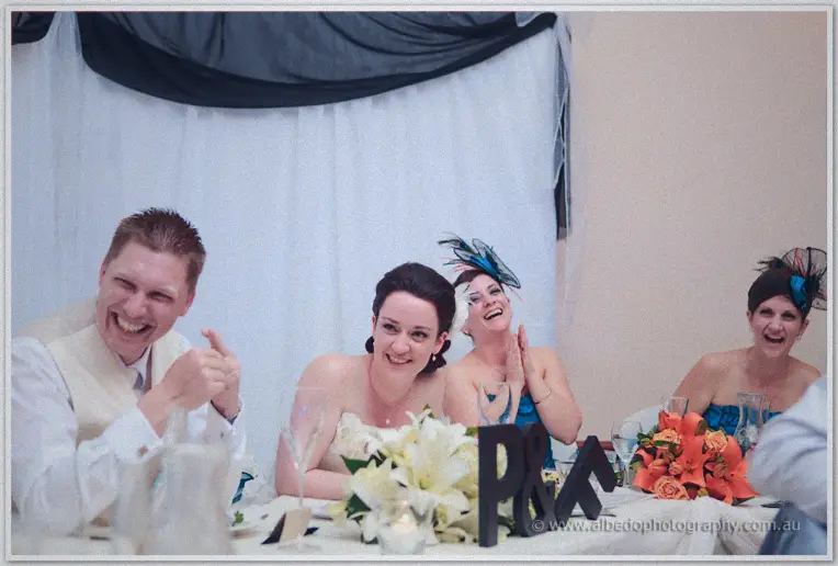 Felicity and Phil share a laugh at the bridal table among guests and white lily centrepieces