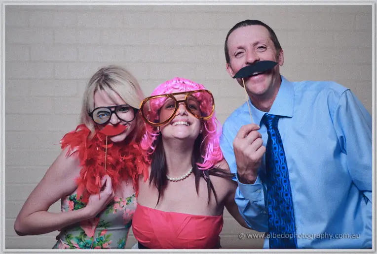Guests in feather boas, novelty glasses and a pink wig ham it up for the photo booth camera