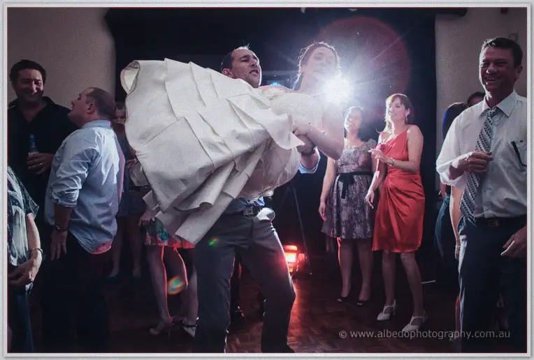 Phil carries a laughing Felicity over his shoulder across the dance floor as guests cheer