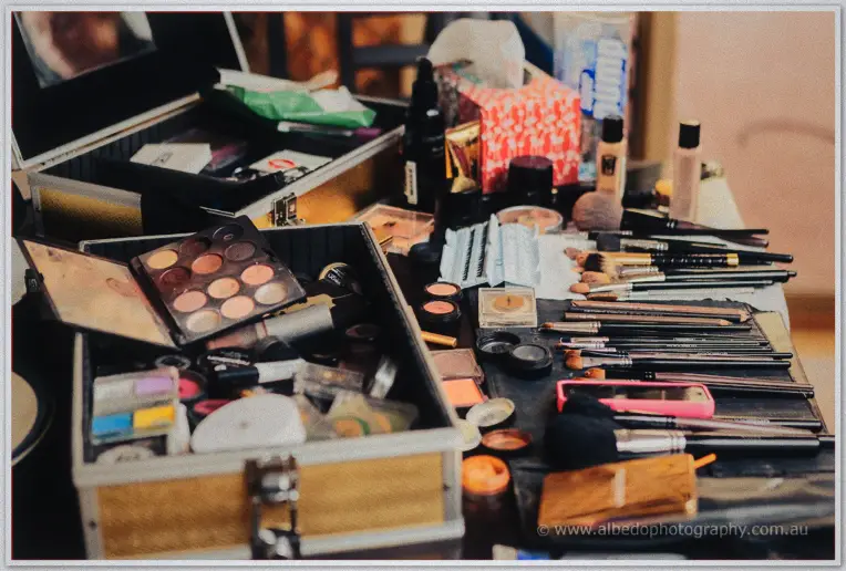 Open makeup cases and brushes crowd a table during Jenna's morning bridal preparations