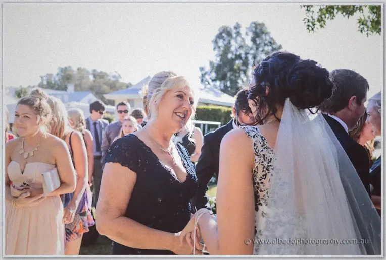 A mother in navy lace laughs as she greets Jenna amid guests after the ceremony